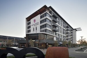 A modern hotel with multiple floors, balconies, and a prominent logo.