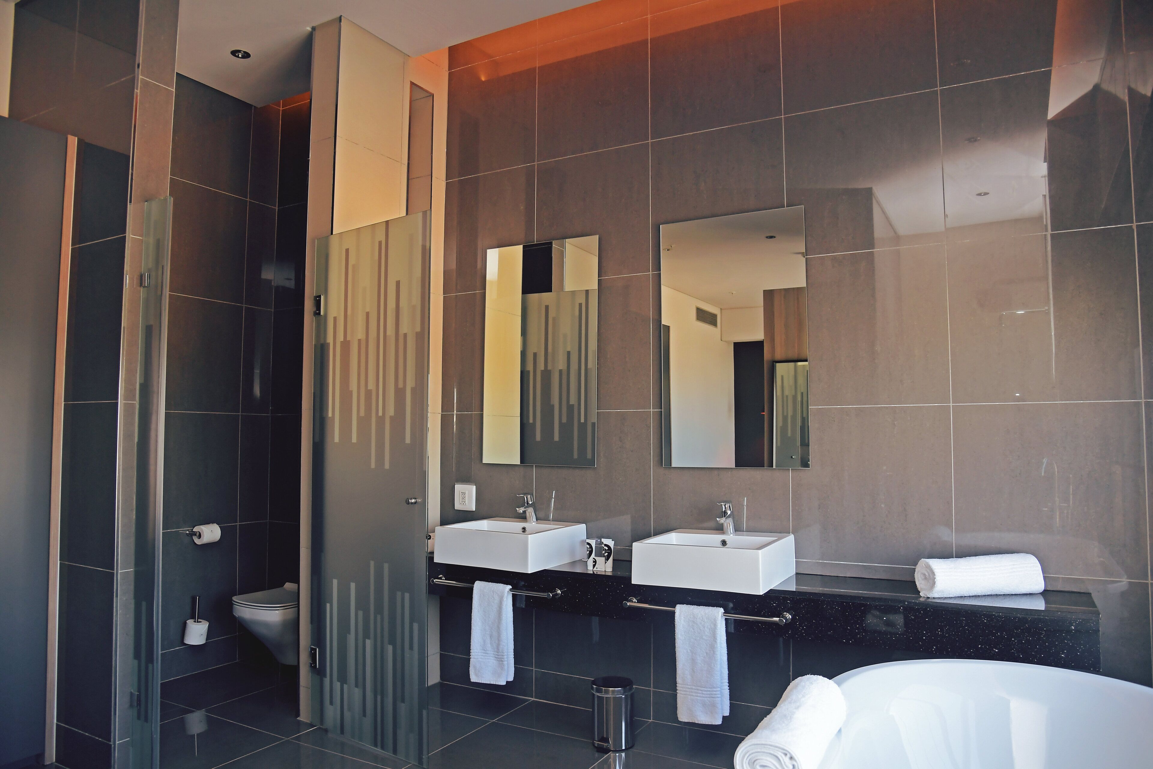 Un baño moderno con dos lavamanos, una cabina de ducha de vidrio y un espejo grande.