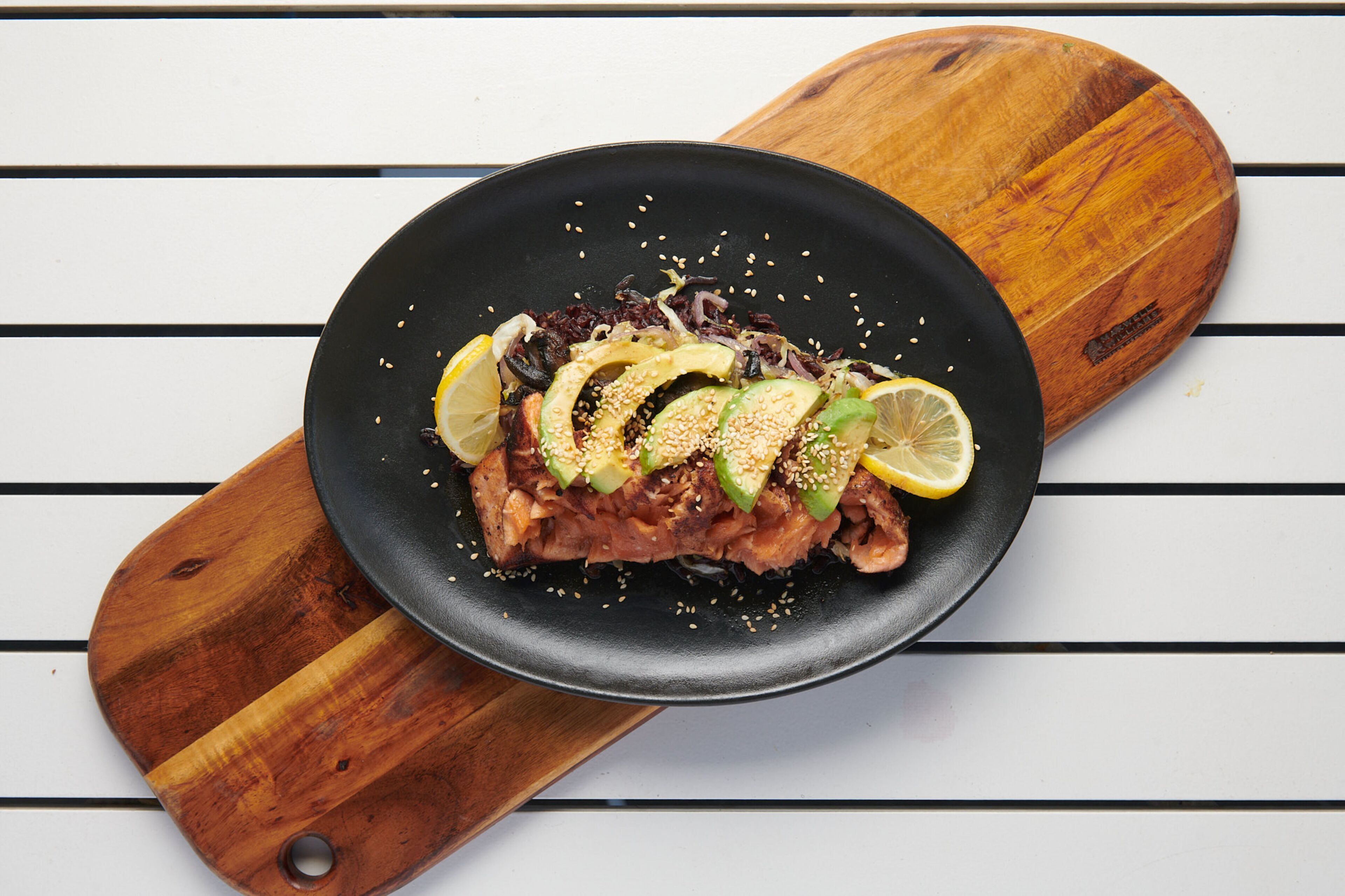 A black plate with a dish on a wooden board.