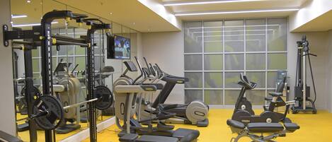 A gym with exercise equipment, mirrors, and a large window.