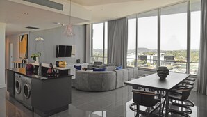 A modern living space with a kitchen, dining area, and large windows offering a city view.