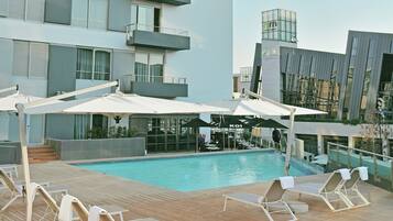 Alberca al aire libre, sombrillas en la alberca y camastros