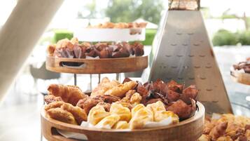 Buffet com diversos pastéis e um ralador de queijo.