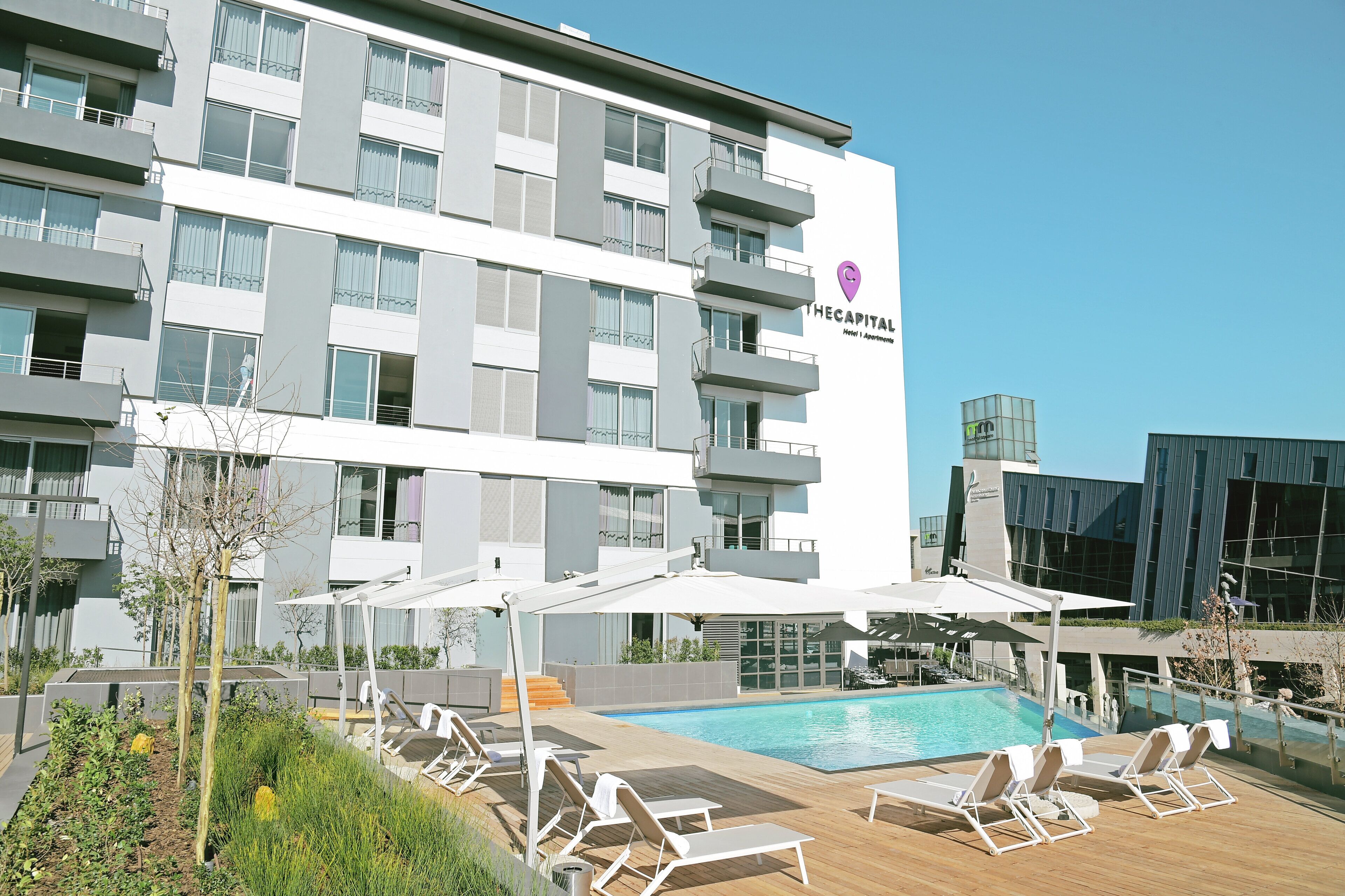 Un hotel con piscina, zona de estar al aire libre y fachada de edificio moderna.
