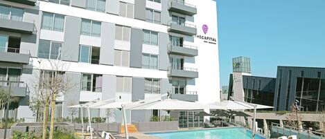 Un hotel con piscina, zona de estar al aire libre y fachada de edificio moderna.