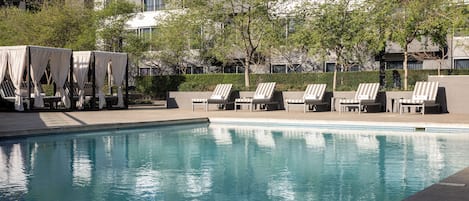 Una piscina al aire libre, sombrillas, sillones reclinables de piscina