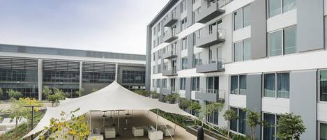 Un edificio moderno con varios balcones y una zona de estar exterior cubierta con macetas.