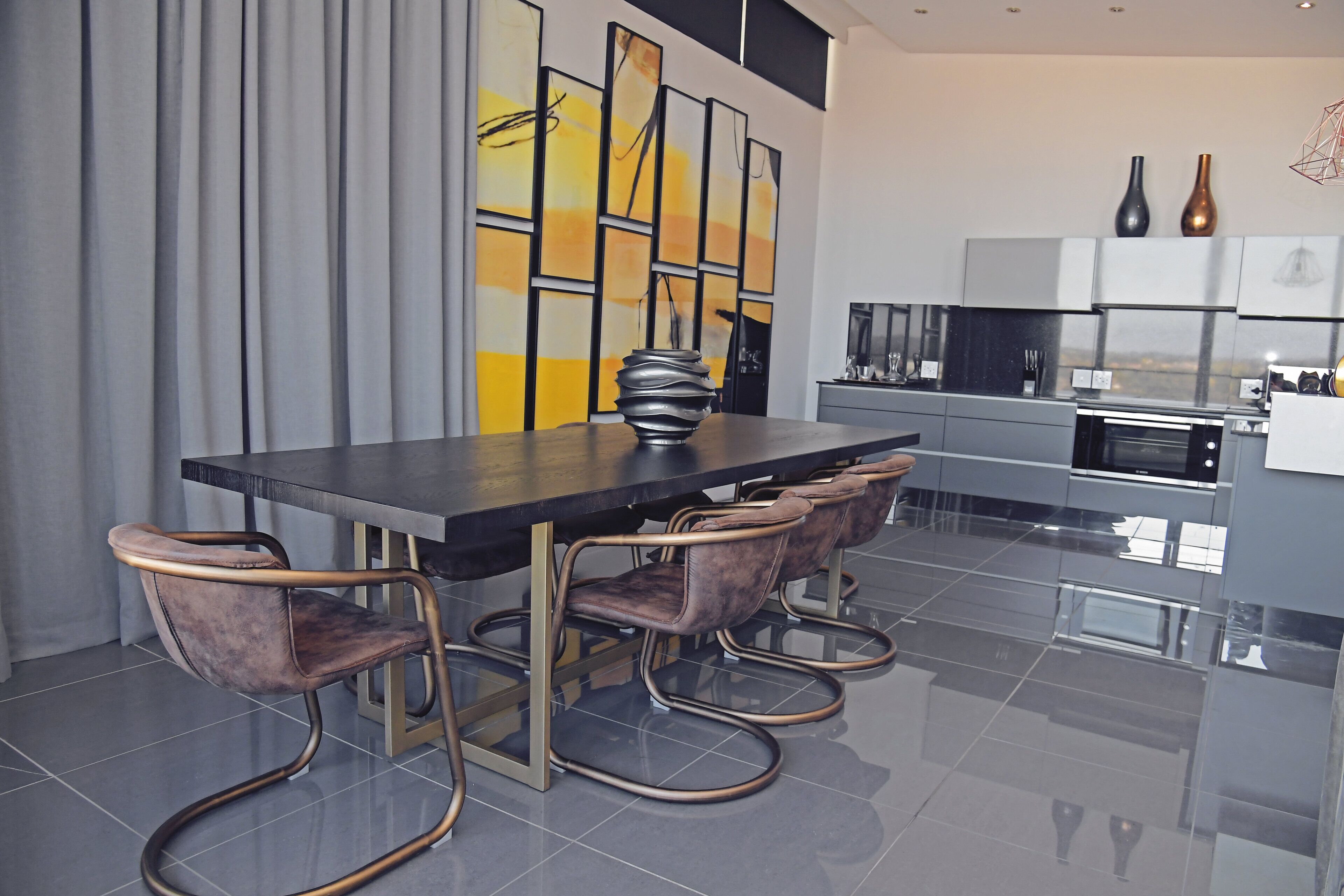 Un comedor moderno con una mesa rectangular, cuatro sillas tapizadas y un centro de mesa decorativo.