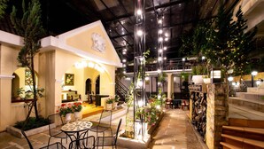 An indoor courtyard with a dining area, staircase, and decorative plants. - Le Petit Paris Hotel Dalat (Cam Ly - Da Lat)