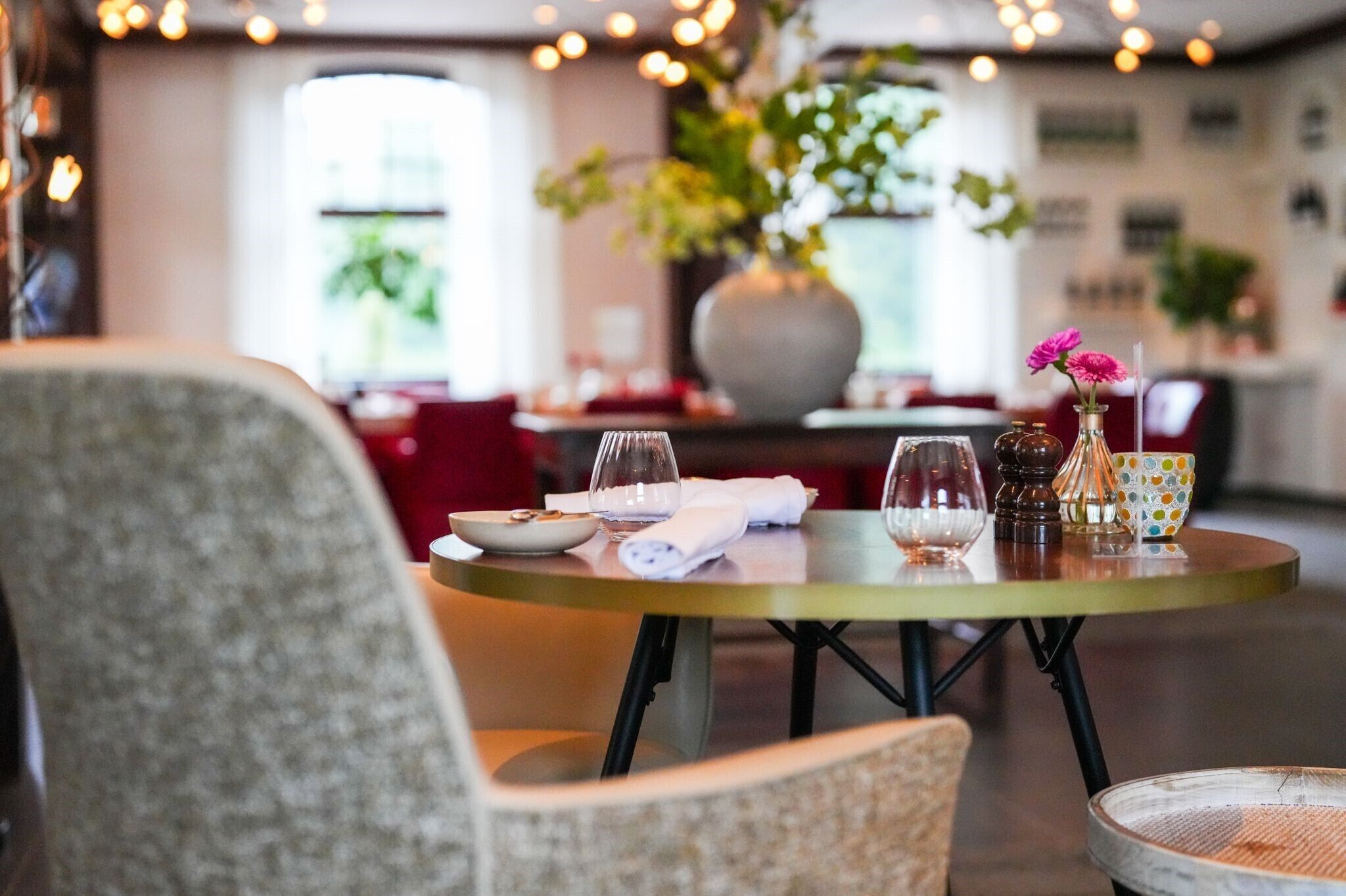 A dining table with a vase of flowers, a bowl, and a glass.