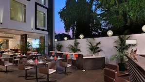 An outdoor dining area with wicker furniture and a bar counter. - Fortune Park Sishmo, Bhubaneswar - Member ITC Hotels' Group (Bhubaneshwar)