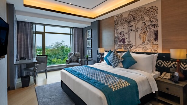 A modern hotel room with a large bed, a desk, and a view of the city. - Fortune Park Sishmo, Bhubaneswar - Member ITC Hotels' Group (Bhubaneshwar)