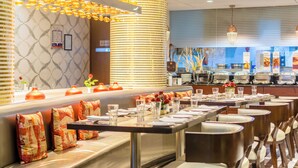 A restaurant with a buffet setup, seating arrangements, and a decorative wall with hanging lights. - Fortune Park Sishmo, Bhubaneswar - Member ITC Hotels' Group (Bhubaneshwar)
