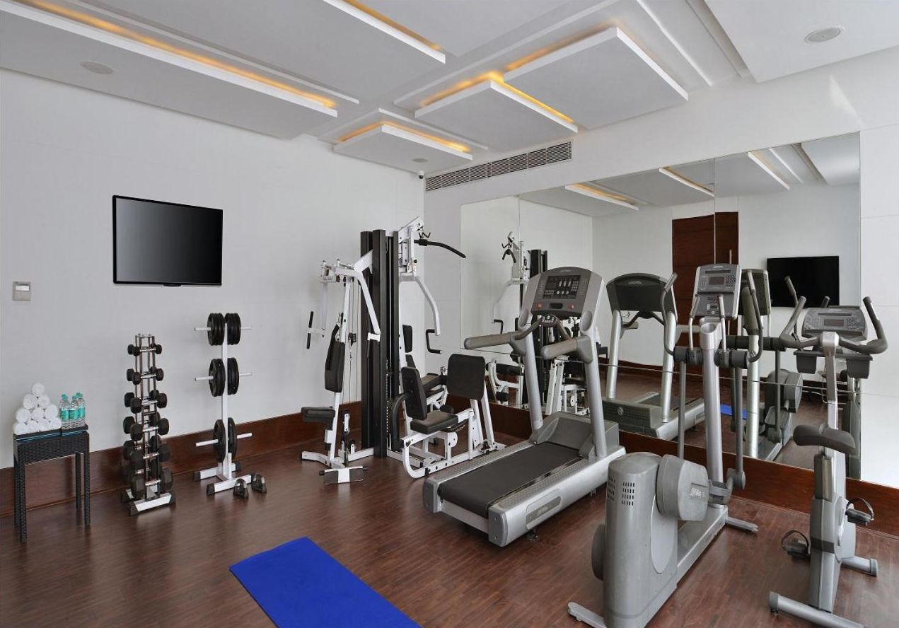A gym with various exercise equipment, a treadmill, and a mirrored wall.