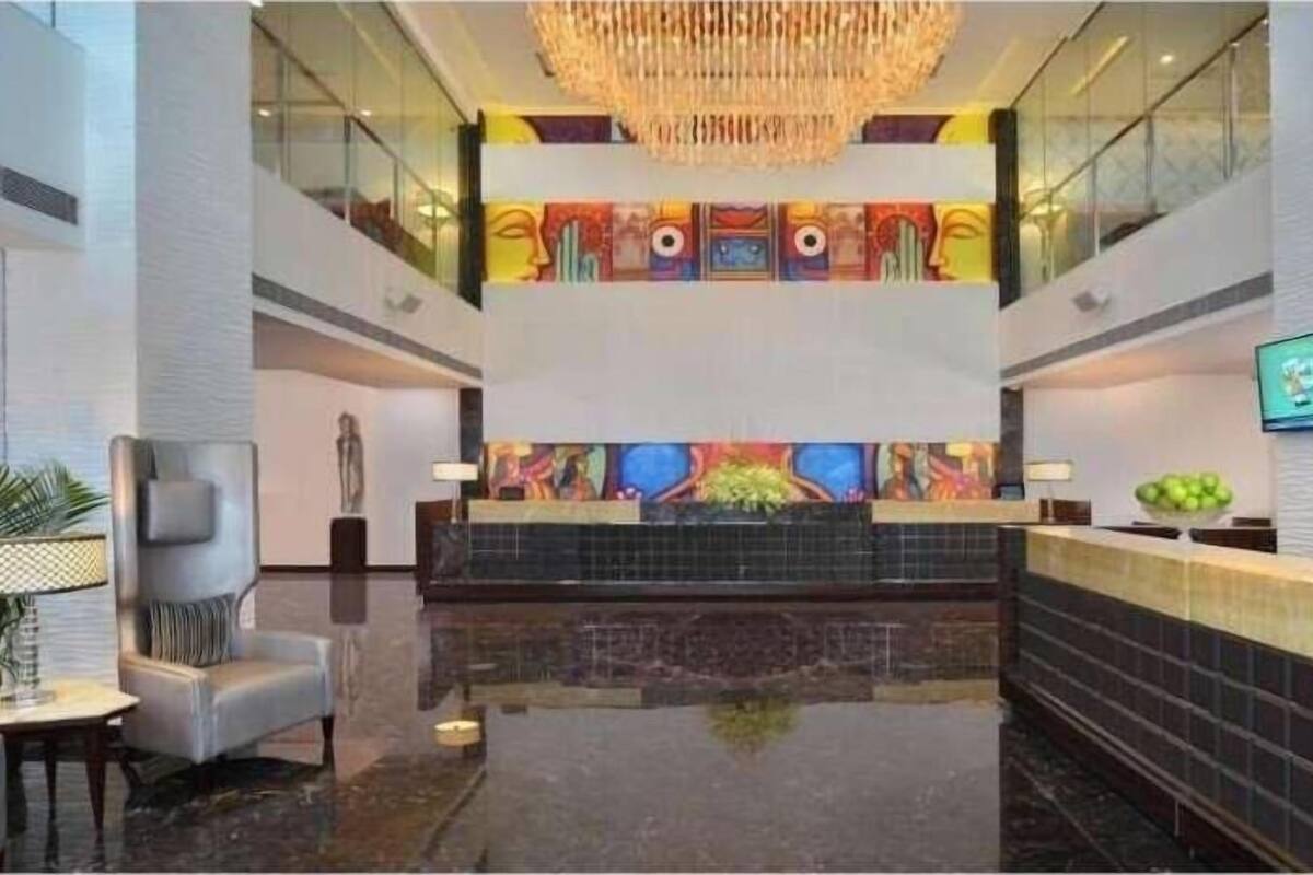 En hotellobby med en receptionsdisk, en sittgrupp och en stor kristallkrona.