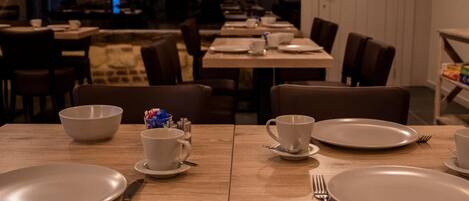 Un comedor con varias mesas dispuestas para comidas, cada una con platos, cubiertos y vasos.