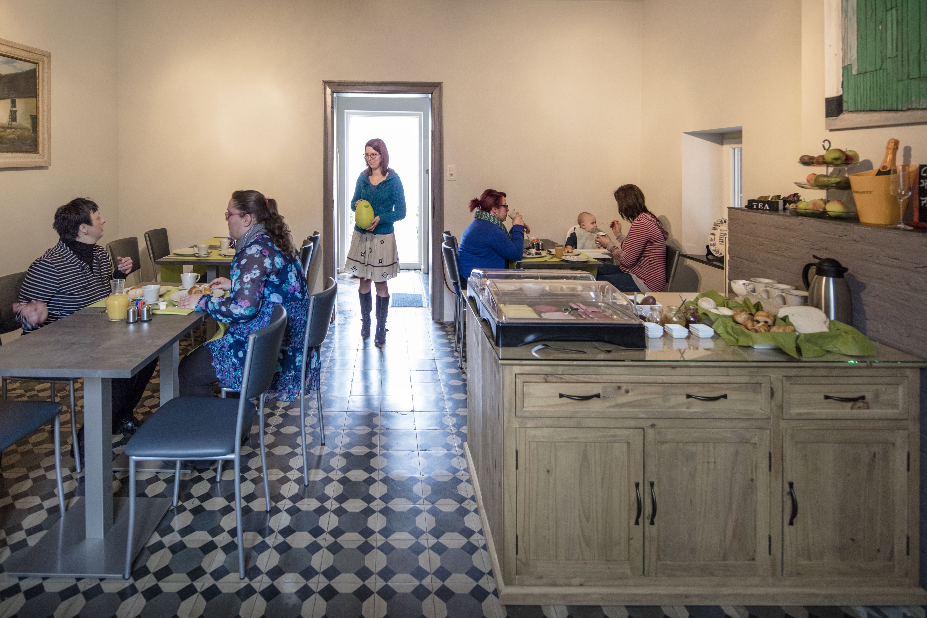 A dining area with a checkered floor, wooden cabinets, and a buffet table.