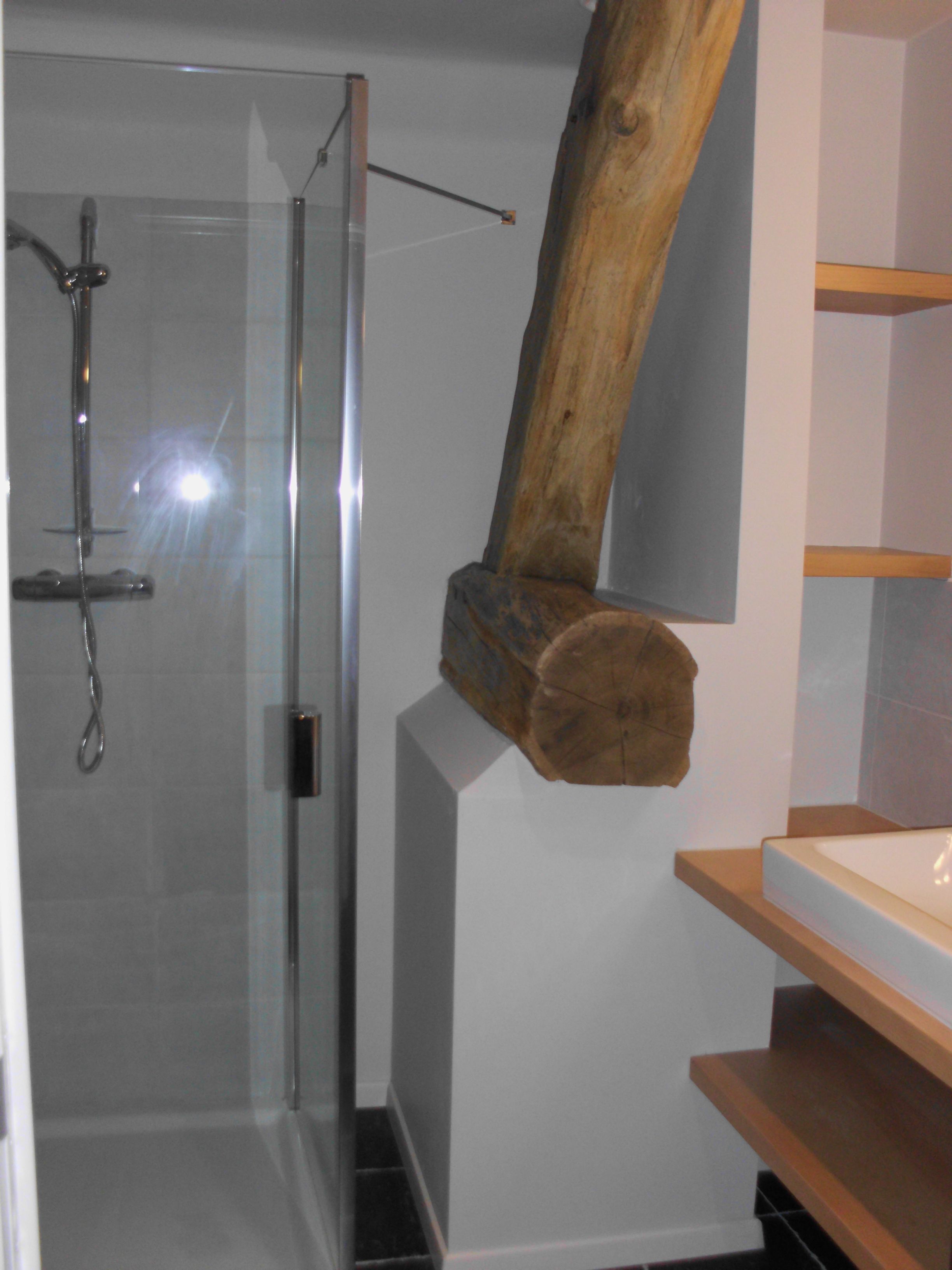 Un baño con cabina de ducha de vidrio, un perchero de madera y un lavabo blanco.
