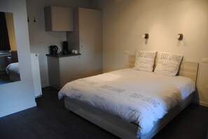 Ein Schlafzimmer mit einem Bett, einer kleinen Küchenzeile und einem Kleiderschrank.