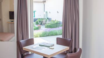 Una habitación con una mesa, sillas, aire acondicionado y vistas a un jardín.