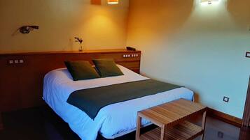 A neatly made bed with a headboard, a bedside table, and two wall-mounted lamps providing light.
