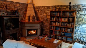 A cozy living room with a stone fireplace, a bookshelf, and a comfortable seating area. - El Rexacu (Onis)