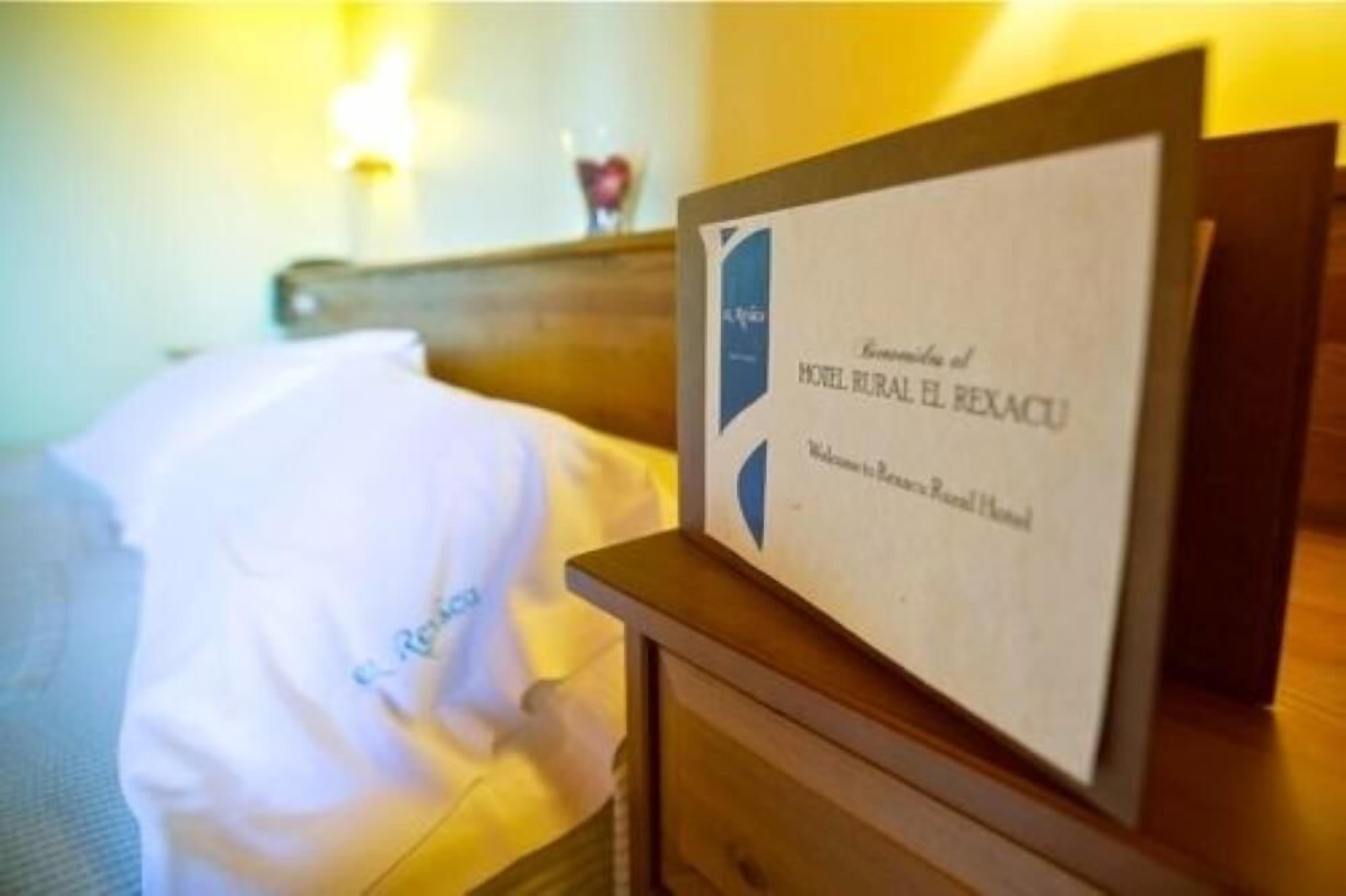 Un cartel de hotel con el nombre 'Hotel Rural El Rexacu' y un mensaje de bienvenida.