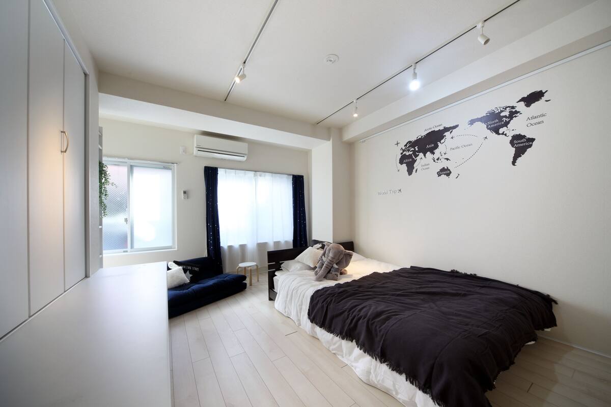 A modern bedroom with a large bed, a world map on the wall, and a window with curtains.