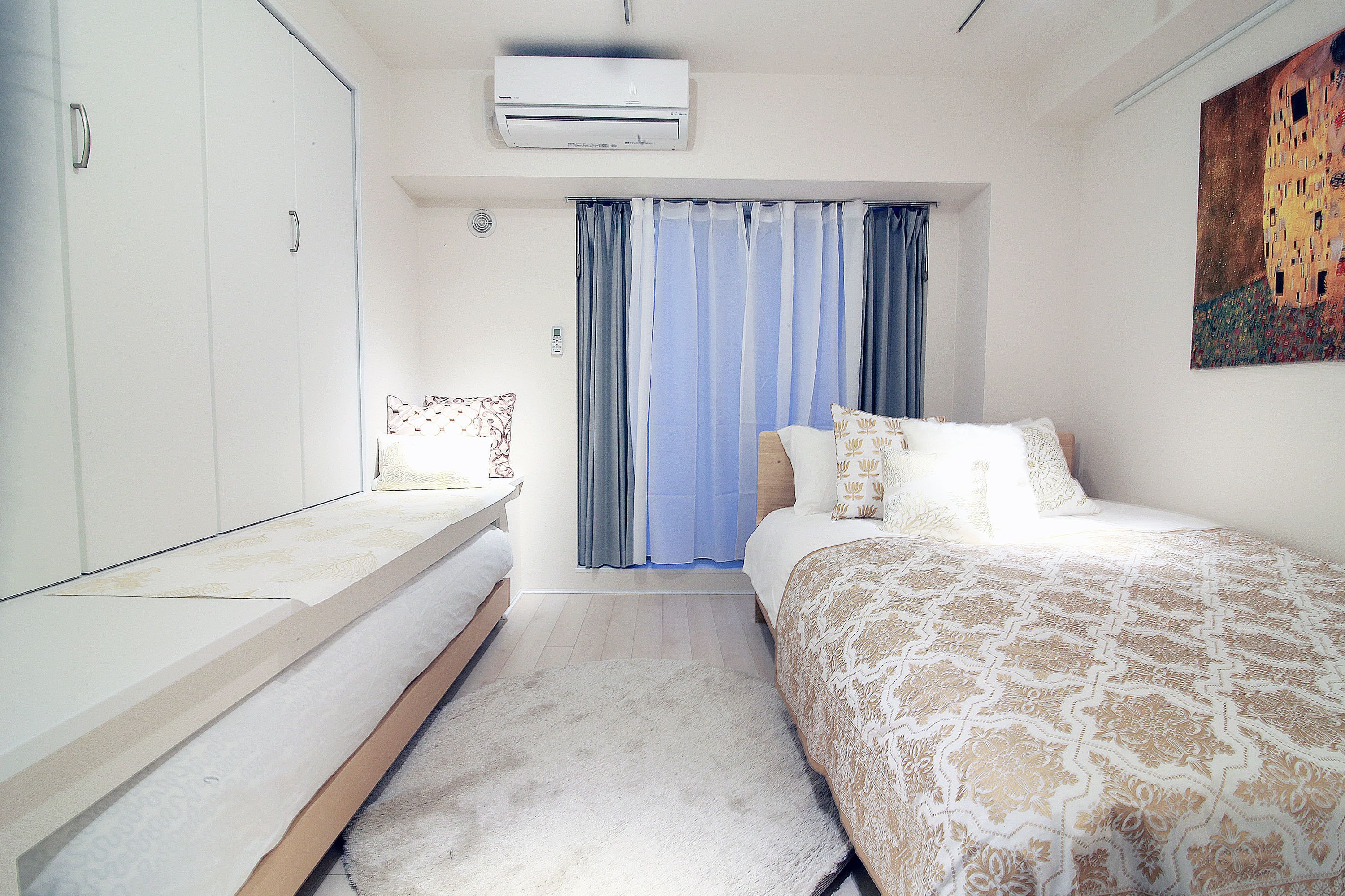 A bedroom with a bed, a bedside table, a wardrobe, and a painting on the wall.