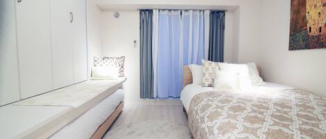 A bedroom with a bed, a bedside table, a wardrobe, and a painting on the wall.