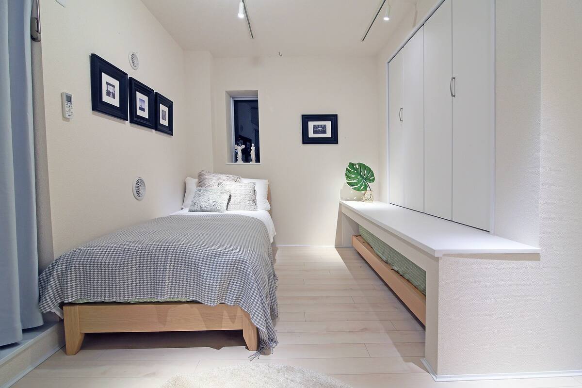 A bedroom with a bed, a bedside table, a window, and a wardrobe.
