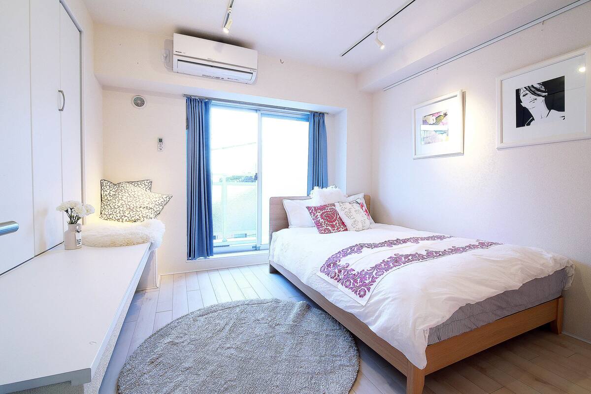 A modern bedroom with a bed, bedside table, and a large window.