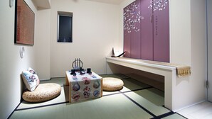 A traditional Japanese room with tatami flooring, a low table with a woven mat, a cushioned bench, and a large purple cabinet with floral decorations. - The Sorapia Tokyo (Tokyo)