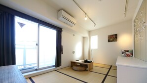 A room with tatami flooring, a futon bed, a small wooden table, and a sliding glass door to the outside. - The Sorapia Tokyo (Tokyo)