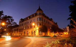 A historic building with a prominent tower, arched windows, and a cobblestone street. - Hotel Kaiserhof (Radeberg)