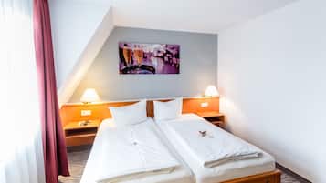 A hotel room with a double bed, two bedside tables, a nightstand, a wall-mounted picture, and a window with curtains.