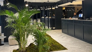 A modern lobby with a reception desk, seating area, and indoor plants. - Shota@Rustaveli Boutique hotel (Tbilisi)