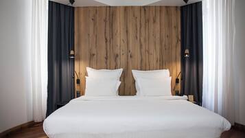 Una habitación de hotel moderna con una cama grande, pared de paneles de madera y dos lámparas de noche.