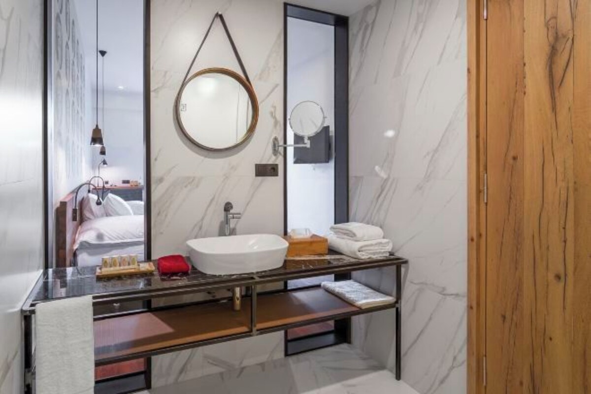 Un baño moderno con un espejo grande, un lavamanos y un mueble de tocador con un perchero para toallas.