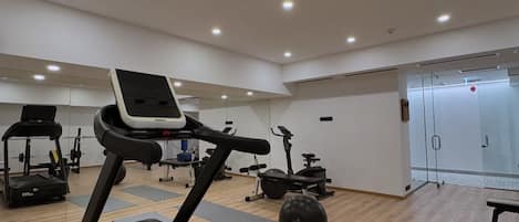 Un gimnasio moderno con cintas de correr, pelotas de ejercicio y máquinas de pesas.