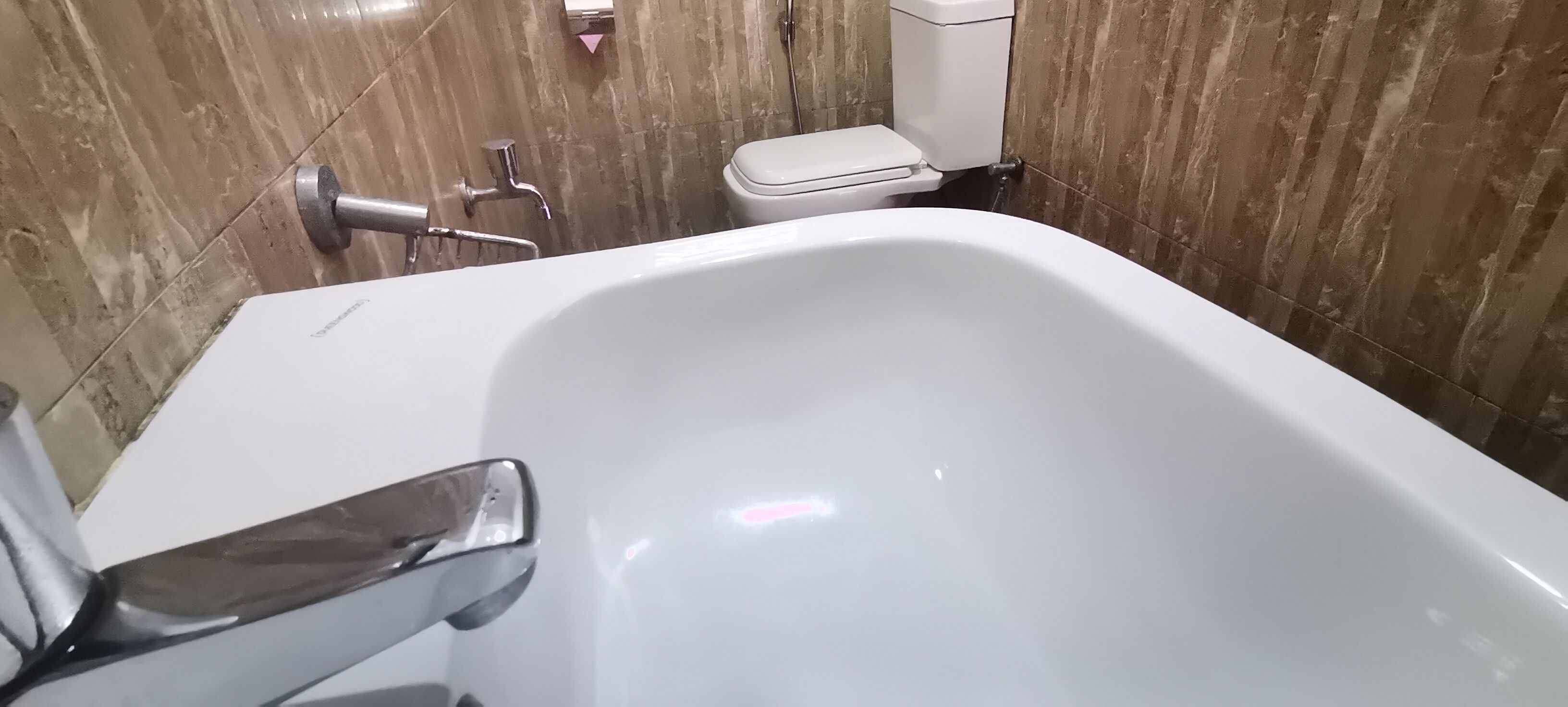 Un baño con una bañera blanca, inodoro y zona de ducha.