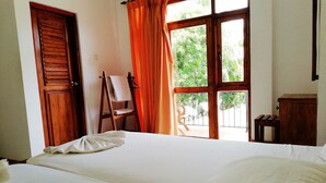 Habitación de hotel con una cama grande, un armario de madera, un caballete y vistas a zonas verdes.