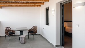 A room with a bed, a table, two chairs, and a small round table. - Villa Libertad (Santorini)