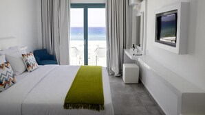 A hotel room with a bed, a green throw, a TV, a bathroom, and a view of the sea. - Amaryllis Beach Hotel (Paros)