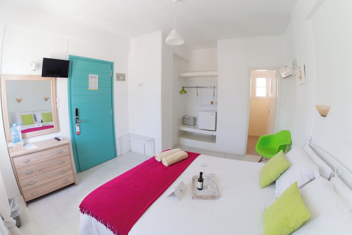 Een hotelkamer met een bed, een bureau, een spiegel, een televisie, een kledingkast en een badkamer.