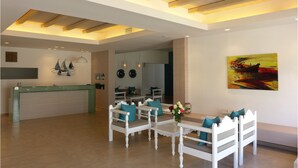 A spacious living area with a wooden ceiling, a reception desk, and a painting on the wall. - Amaryllis Beach Hotel (Paros)