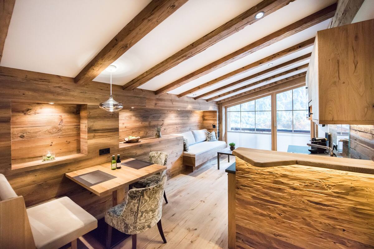 A cozy cabin-style room with a wooden interior, a dining area, and a large window offering a view of the outdoors.