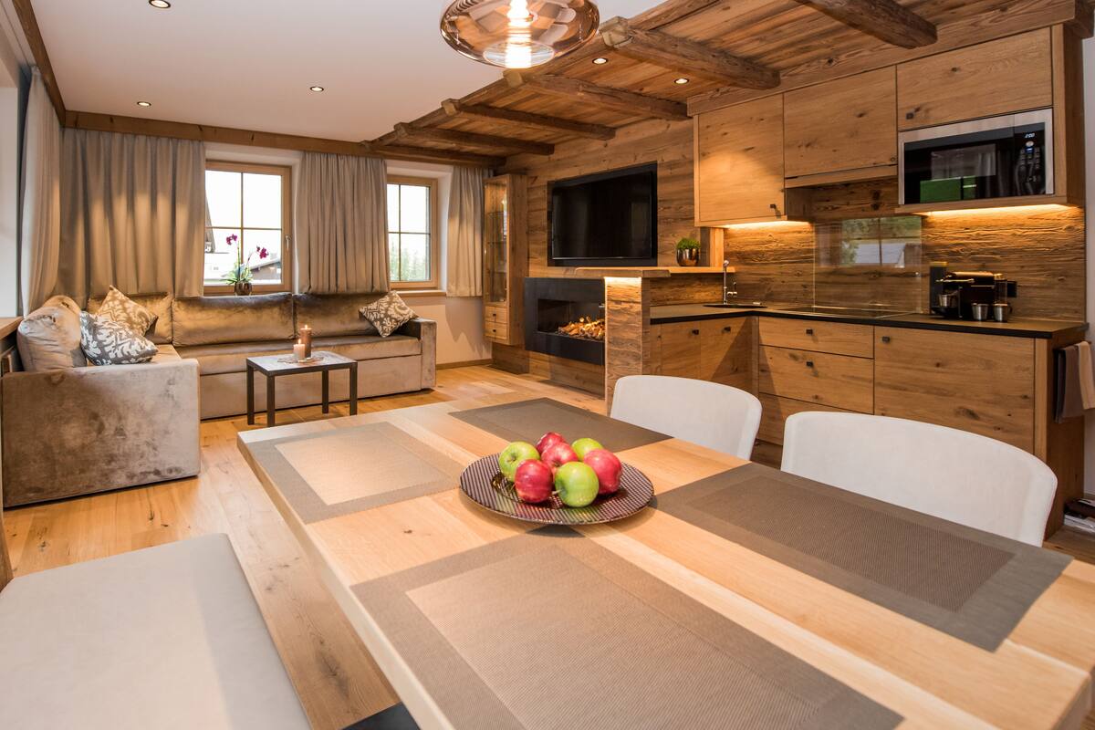 A modern kitchen with wooden cabinets, a built-in microwave, and a dining area with a table set for four.