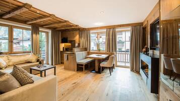 Un vaste espace de vie doté d’un plafond en bois, d’une table à manger avec des chaises, d’un canapé et d’une cheminée.