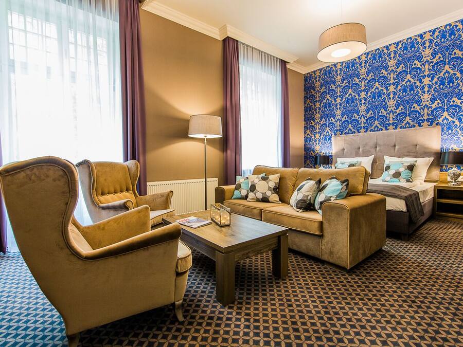 Ein Hotelzimmer mit einer Couch, einem Sessel und einem Bett mit Kopfteil.
